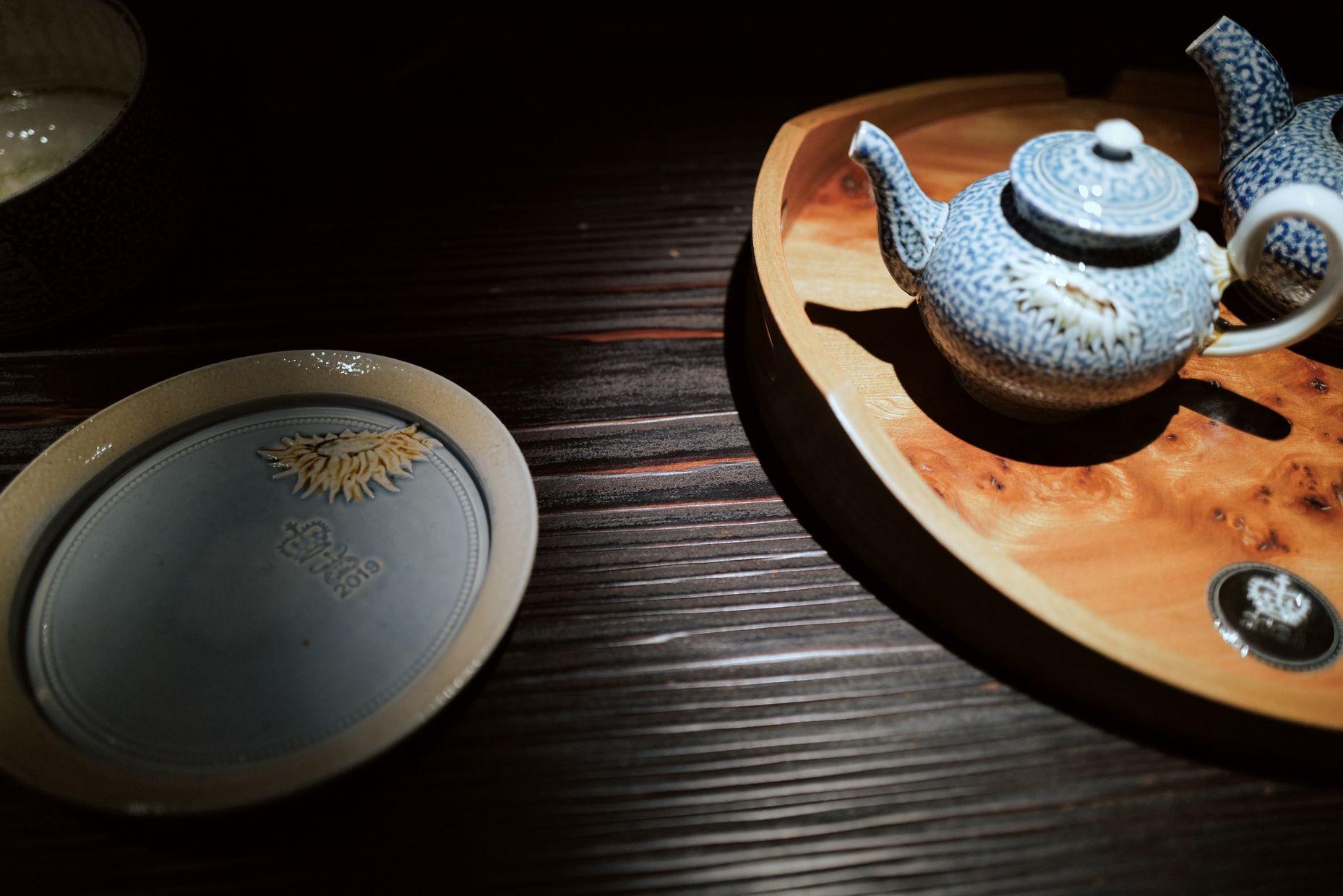 Steve Harrison Tea Ceremony: two speckled blue salt-glazed teapots on a burl-wood tray beside a stamped plate.