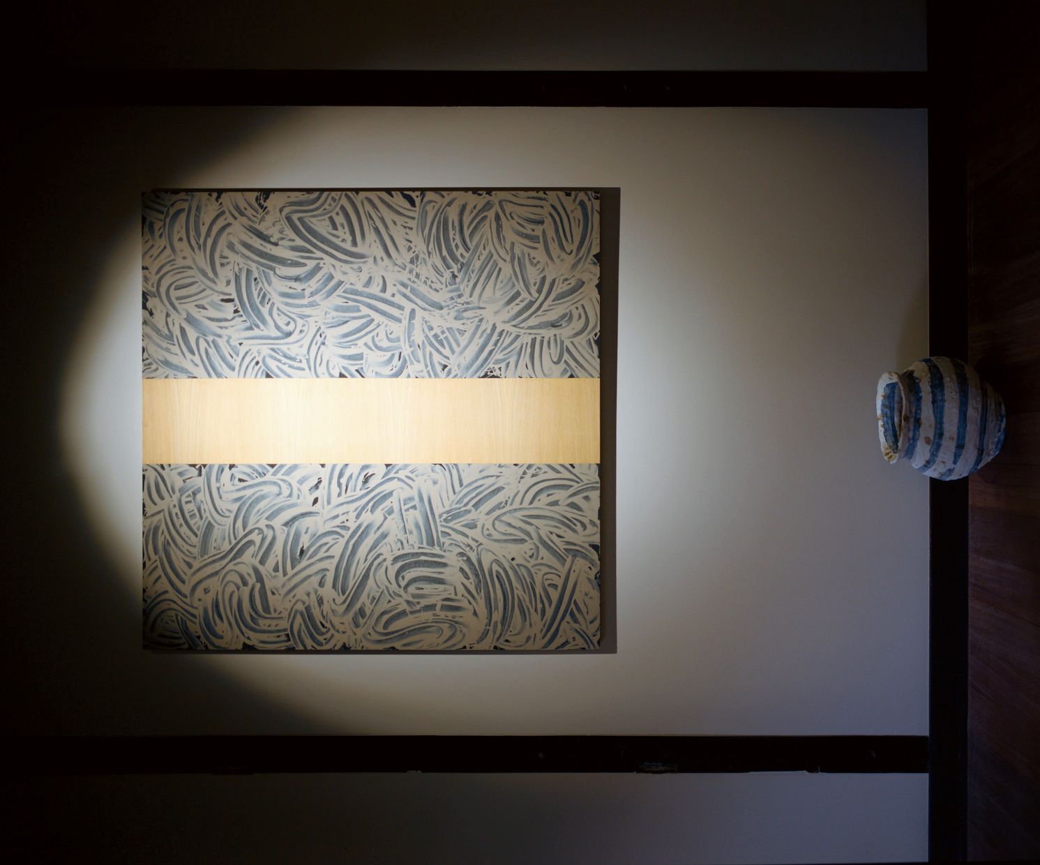 A square mud work by Richard Long lit by a single spotlight.